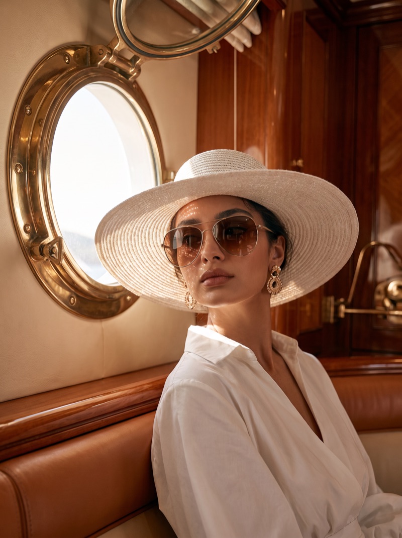 The model seated in the panelled saloon beside a brass porthole