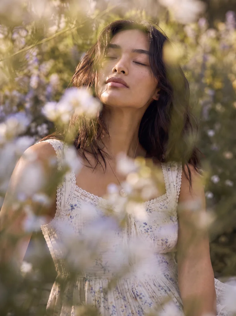 Previs frame: the model in a tiered white dress, eyes closed among the white blossom